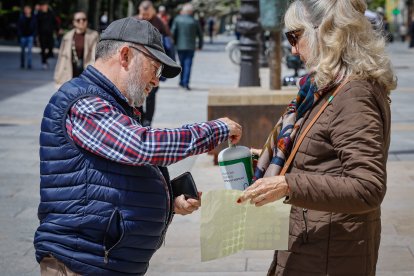 Un hombre colabora con la causa metiendo dinero en una hucha.
