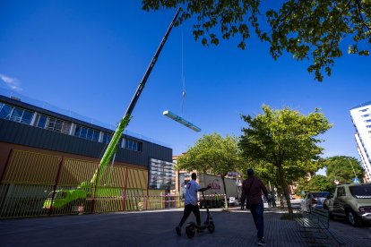 Una grúa descarga material para la obra de renovación de la cubierta del polideportivo Lavaderos.