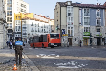 Un agente de servicio en la plaza del Cid, mientras al fondo pasa un autobús municipal.