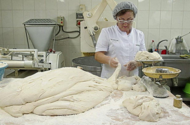Encarna Terrón corta porciones de masa, que pesa en una balanza tradicional, en la panadería de Carbajales de Alba (Zamora).-MIRIAM DENEIVA