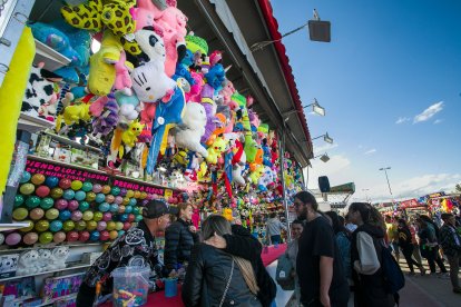 Un grupo de personas juega a los globos en un puesto. T. ALONSO