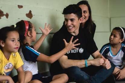 Marc Márquez atiende las explicaciones de los niños en una favela de Sao Paulo.