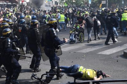 Una manifestante yace en el suelo durante los choques entre la policía y los 'chalecos amarillos' este sábado en París