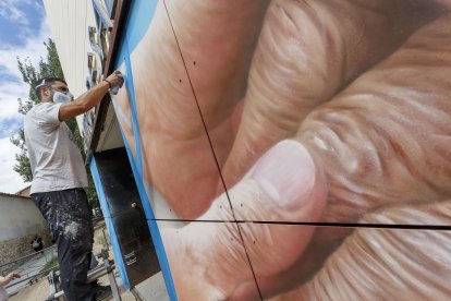 Christian Saldaña trabaja en el mural que está rematando en el centro de Salud de Santa Clara. FOTOS: © ECB / SANTI OTERO