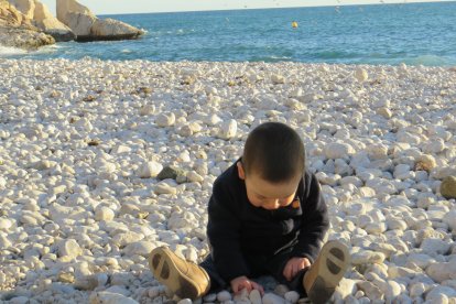 Un niño juega con piedras en la playa. ECB