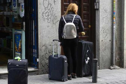 Una mujer accede a un portal de un apartamento turístico.-
