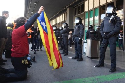 Una manifestante muestra una 'senyera' a los agentes de los Mossos que custodian la estación de Sants.