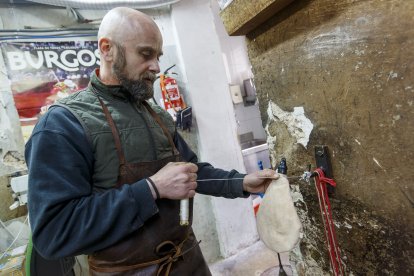 Jorge realiza el atado de una bota en el taller.
