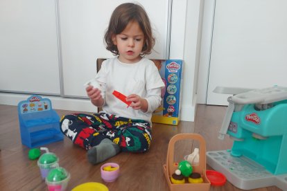 Una niña juega con ss regalos de Reyes Magos. ECB