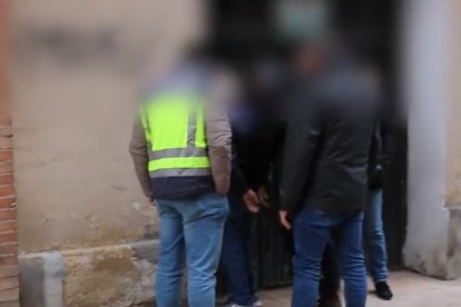 El detenido junto a los agentes durante el registro de su domicilio. POLICÍA NACIONAL