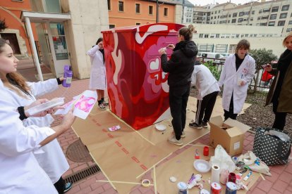 Diez estudiantes de Arte durante la intervención diseñada por Jana del Val en uno de los contenedores de recogida de ropa usada de Cáritas. TOMÁS ALONSO
