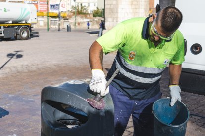 Un operario de Urbaser muestra como se limpian las pintadas vandálicas sobre una papelera, en el entorno de la Real y Antigua de Gamonal.