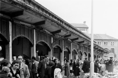 Personas comprando ramos de flores para el Día de Todos los Santos en el antiguo mercado existente en la Calle General Santocildes archivo municipal.