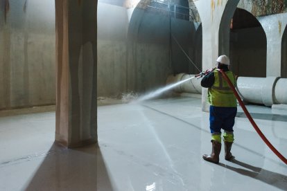 Un operario, manguera en hombro, para controlar la fuerte presión del agua.