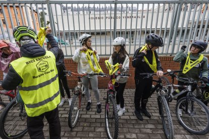 Un voluntario entrega un reflectante a los escolares.