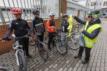 Un voluntario entrega un reflectante a los escolares.