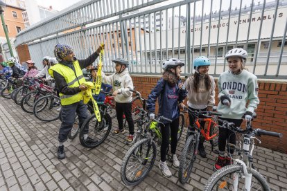Un voluntario entrega un reflectante a los escolares.