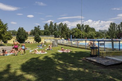 Varias familias disfrutan de la zona de sombra en las piscinas municipales de verano de El Plantío.