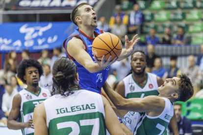 Joe Cremo lanza a canasta rodeado de rivales.