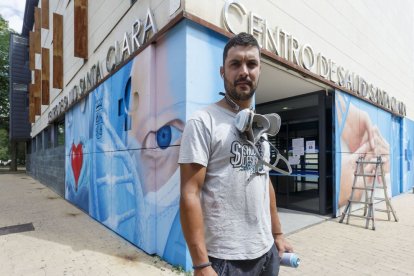 Christian Sasa posa delante de otro de sus murales.