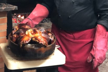 Urbano Arciniega posa con un cochinillo cocinado en horno de piedra.