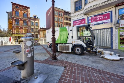 Una máquina de limpieza de calles pasa por detrás de una fuente vandalizada.