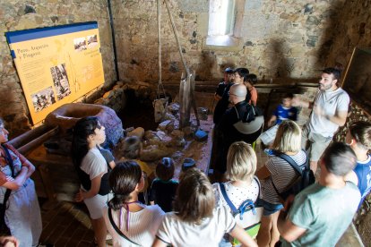 Grupo de visitantes frente a la recreación de una caña o pozo.