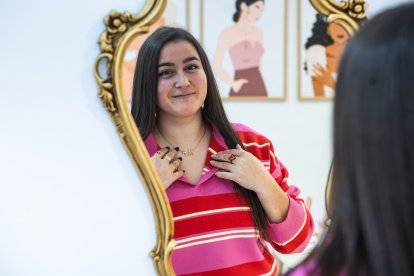 María se mira al espejo mostrando su collar de la Catedral.