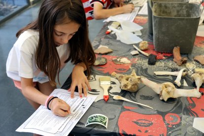 Una joven investigadora recaba datos de los restos encontrados en un enterramiento.