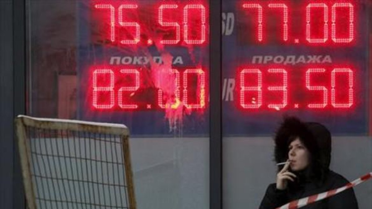 Una mujer, ante un panel que muestra el cambio del rublo ante el euro y el dólar, en Moscú.-REUTERS / SERGEI KARPUKHIN