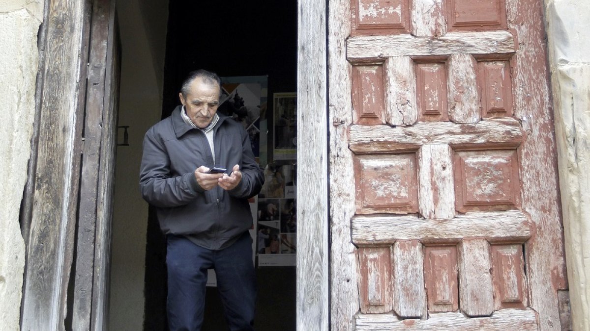Un hombre intenta encontrar cobertura para su teléfono móvil en un pueblo. TEJEDOR