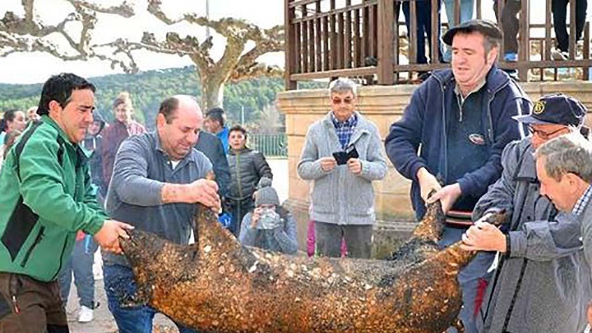 Cuatro hombres posan el cerdo sobre una tabla para proceder a su despiece.-ECB