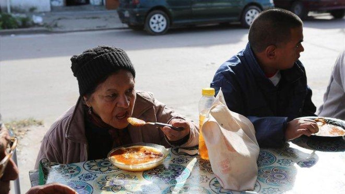 Una mujer y un hombre se alimentan en un comedor social de Villa Fiorito, en Buenos Aires, el pasado mes de junio.-RODRIGO GARCÍA (EFE)