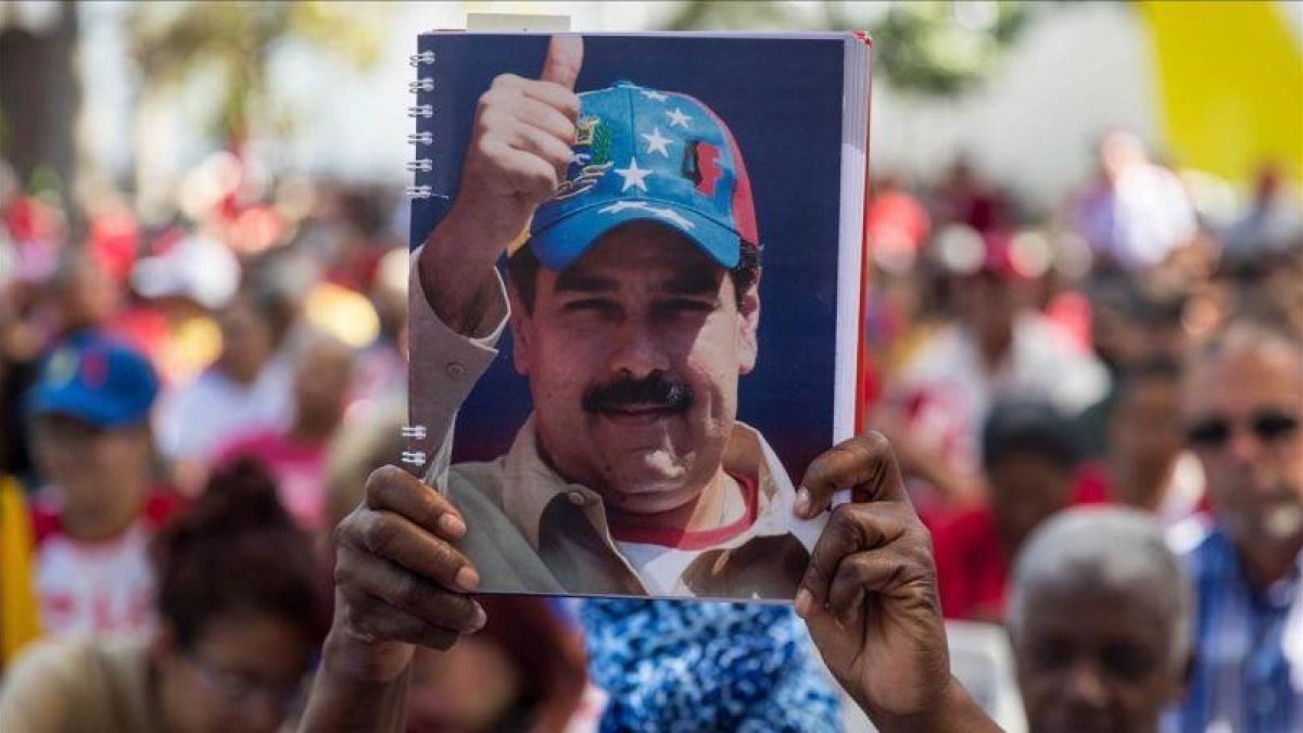 Una mujer seguidora del oficialismo venezolano sostiene una fotografía del presidente Nicolás Maduro el pasado sábado.-EFE / MIGUEL GURIERREZ