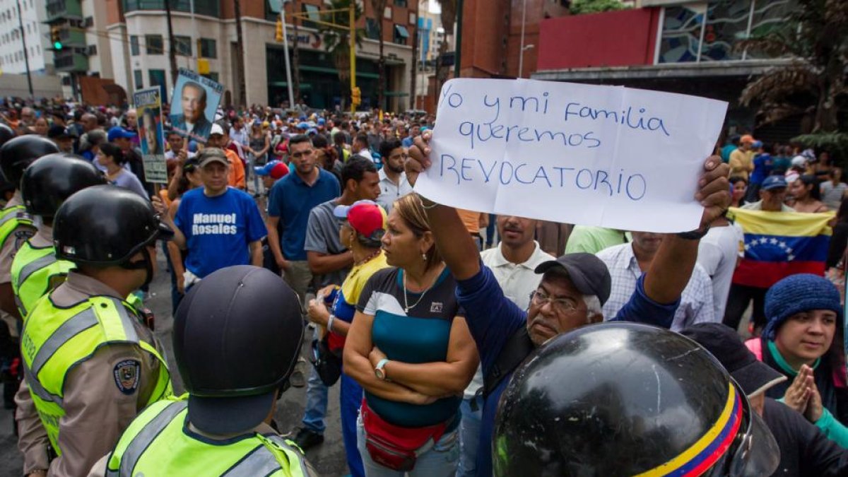 Un grupo de personas protesta frente a miembros de la Policía Nacional Bolivariana (PNB) en la ciudad de Caracas (Venezuela).-EFE / MIGUEL GUTIERREZ