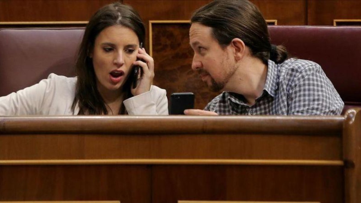 Pablo Iglesias muestra el móvil a Irene Montero durante el pleno en el Congreso.-JOSÉ LUIS ROCA