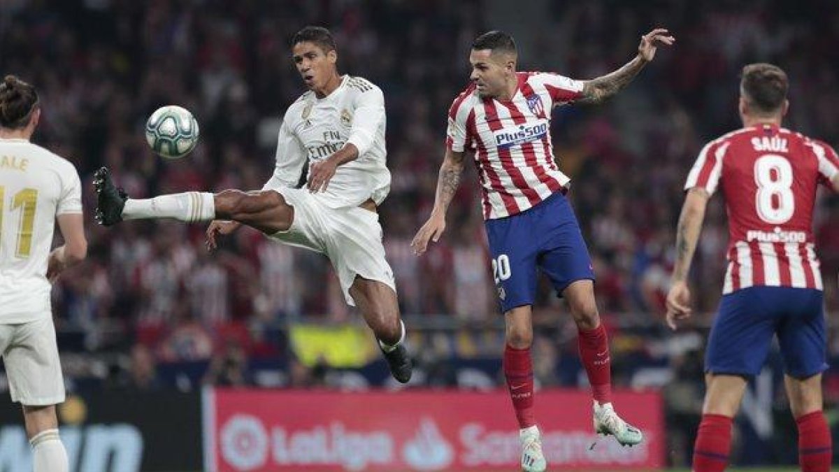El madridista Varane (i) golpea un balón en el partido ante el Atlético de Madrid.-AP