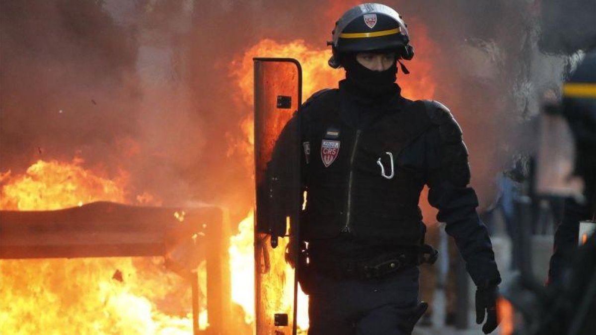 Un policía antidisturbios camina cerca del fuego de una barricada en Toulouse.-EFE / GUILLAUNE HORCAJUELO