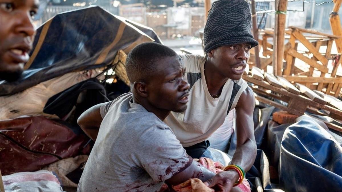 Un hombre ayuda a un herido a salir de una de las zonas conflictivas en el marco de las protestas por el resultado de los comicios en Zimbabue.-YESHIEL PANCHIA (EFE)