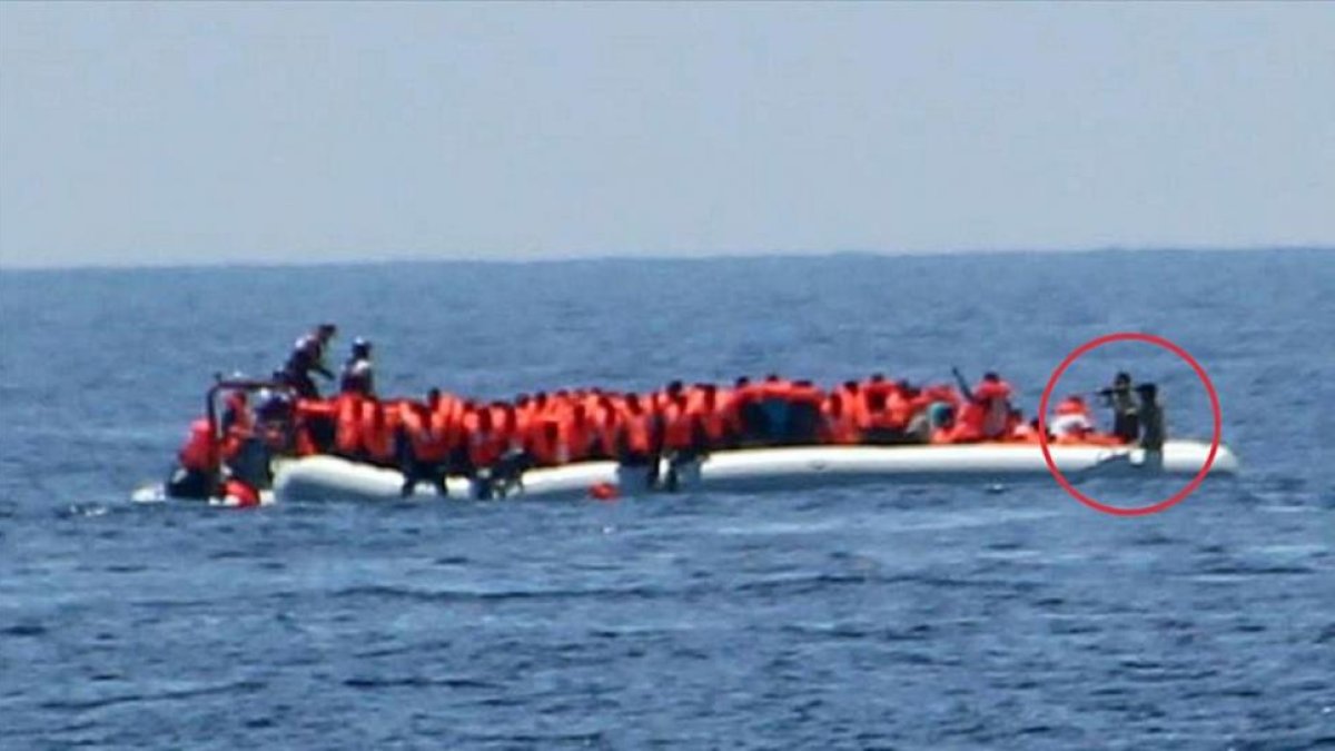 Imagen de la oenegé Jugen Rettet donde se ve a unos guardacostas libios apuntando a unos refugiados.-JUGEND RETTET