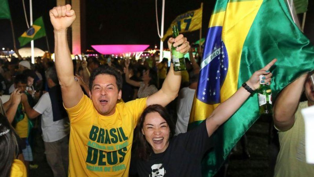 Con camisetas verdes y amarillas y banderas de Brasil, los seguidores celebran el triunfo de Bolsonaro.-AFP