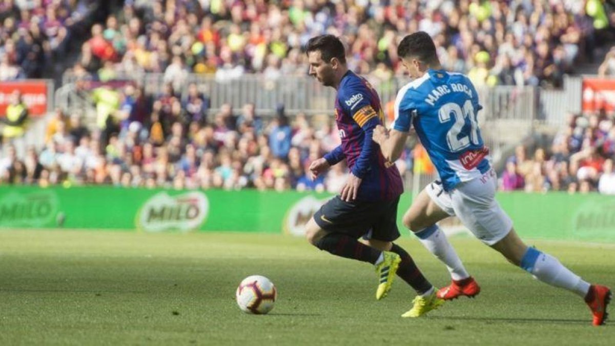 Messi, perseguido por Marc Roca en una acción del derbi.-JORDI COTRINA
