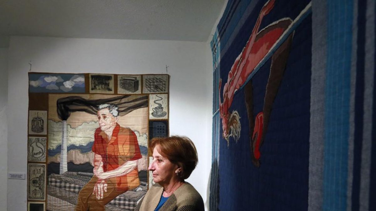 Mayra Alpízar posa junto a un retrato de su padre y ‘El salto’, un bordado de su trabajo feminista.-Raúl Ochoa