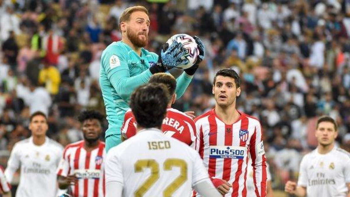 El portero del Atlético Jan Oblak detiene un balón durante el partido ante el Madrid.-AFP