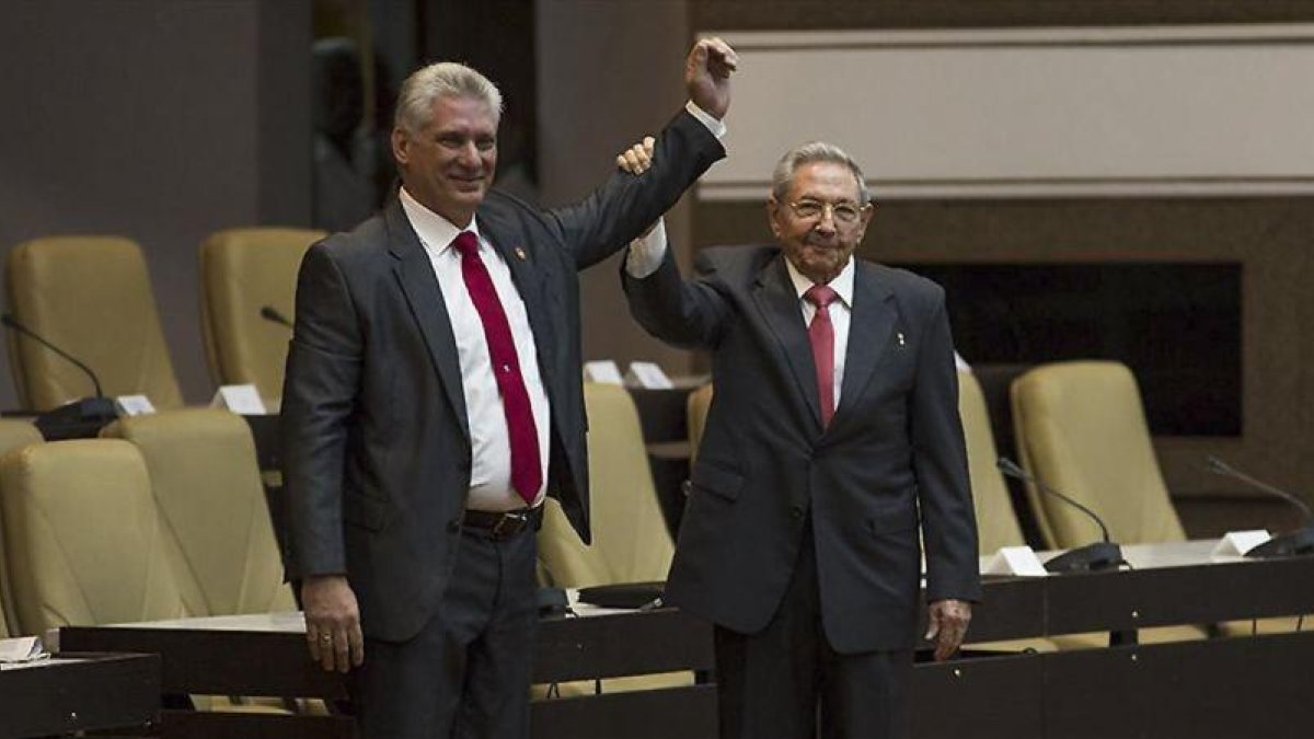 Raúl Castro (derecha) levanta el brazo del nuevo presidente de Cuba, tras ser nombrado oficialmente por la Asamblea Nacional, en La Habana, el 19 de abril.-AFP