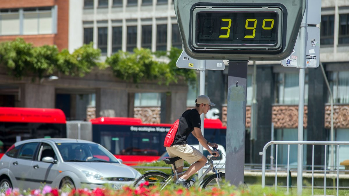 Un ciclista y varios coches pasan junto a un termómetro a 39ºC en Burgos capital.