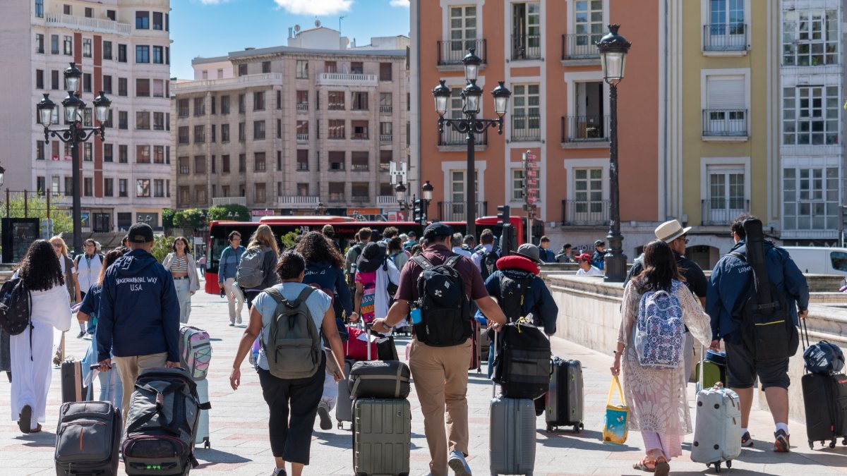 Un grupo de turistas con maletas cruza por el puente Santa María de la capital burgalesa.