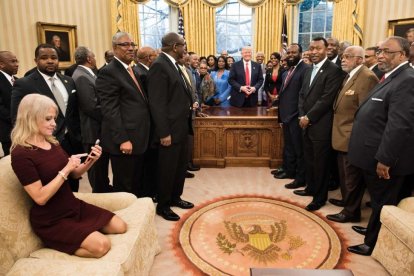 Kellyanne Conway, de rodillas y con zapatos, consulta su móvil mientras Trump y sus invitados posan para la foto oficial-AFP