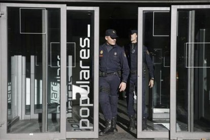 Dos policías salen de la sede central del PP, en la calle Génova de Madrid.-