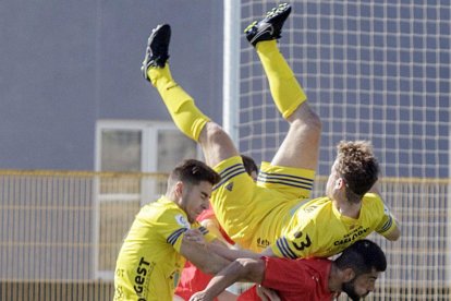 El jugador del Atrio Germán Marijuán cae sobre el defensa delRealBurgos Javier Junyent, ayer, en San Amaro.-SANTI OTERO